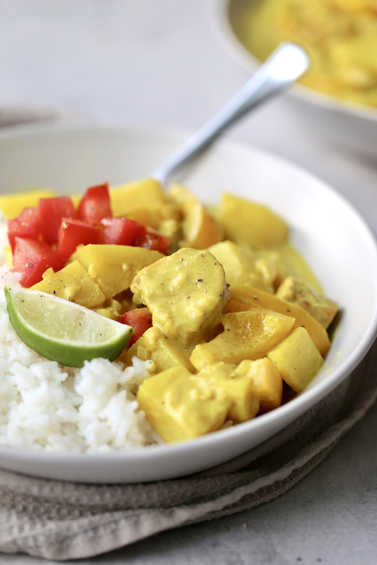 non-spicy vegan massaman curry served with steamed rice, chopped tomatoes and a wedge of lime