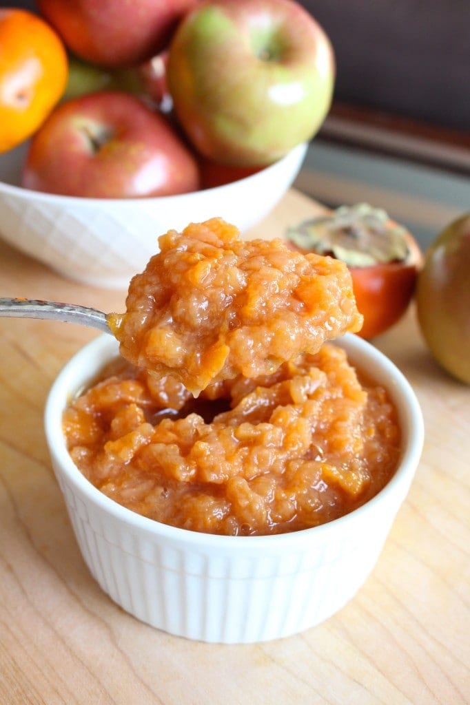 crockpot applesauce with persimmons being scooped up with a spoon
