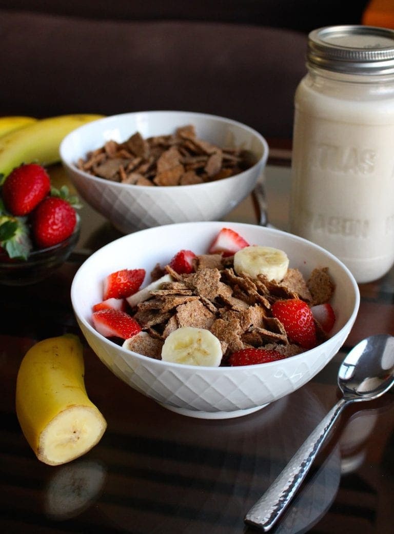 Homemade Bran Flakes Cereal in a white bowl with strawberries and bananas on top.