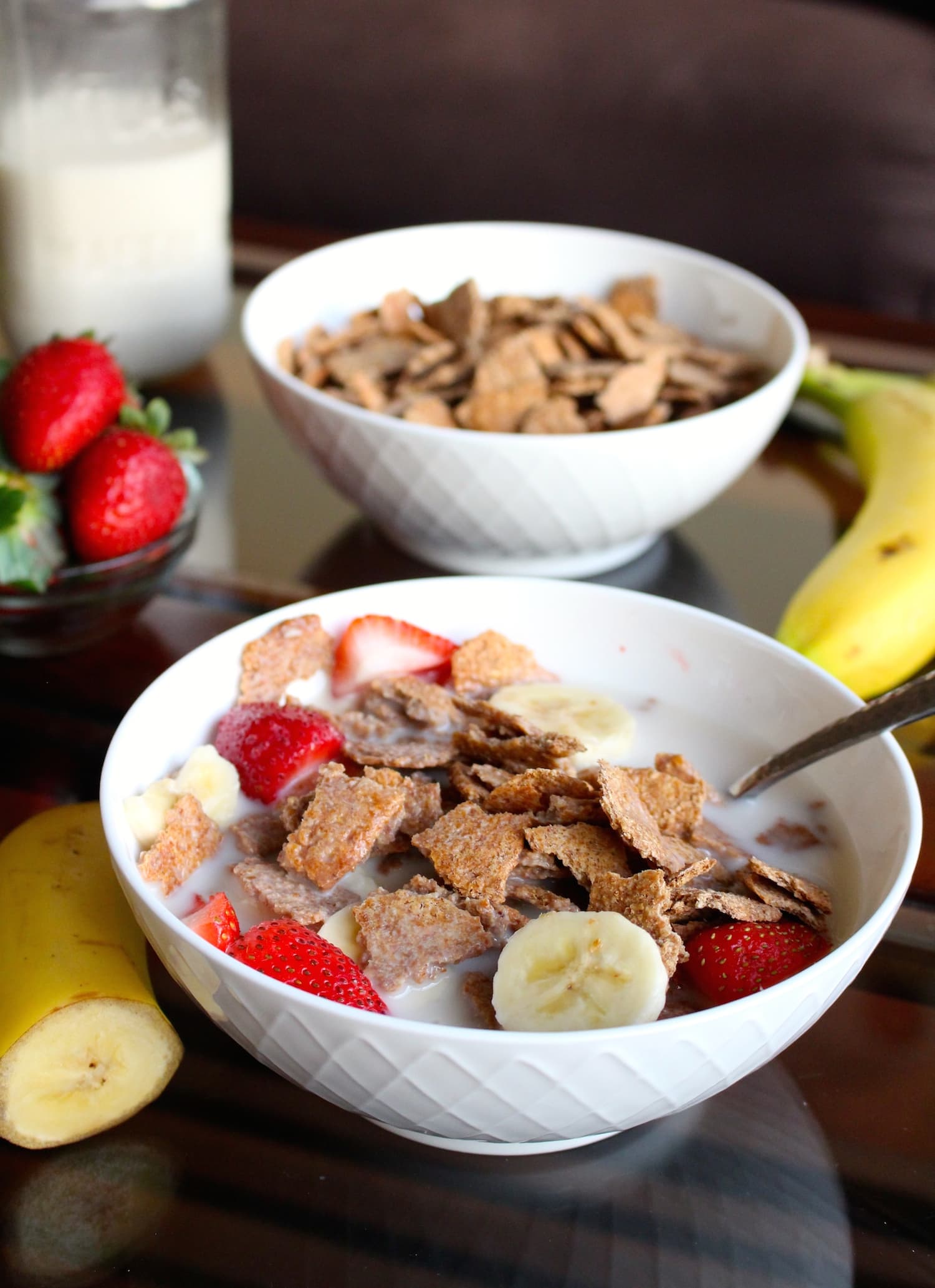 Homemade Bran Flakes Cereal in a white bowl topped with almond milk, sliced banana and strawberries.