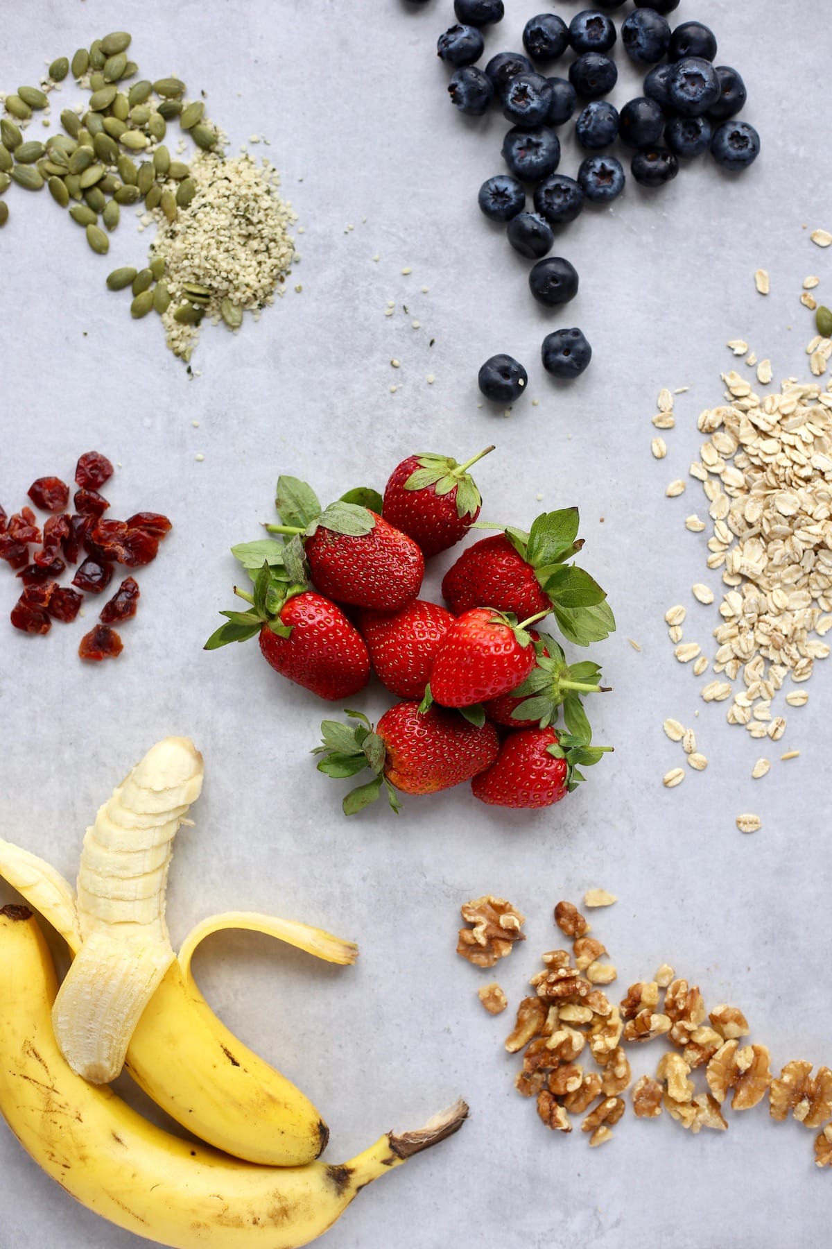 Berries, bananas, nuts, seeds, oats and dried fruit beautifully displayed on a table