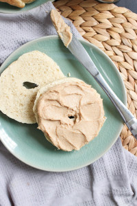 Dairy-Free Cinnamon Maple Cream Cheese spread thick on a homemade bagel