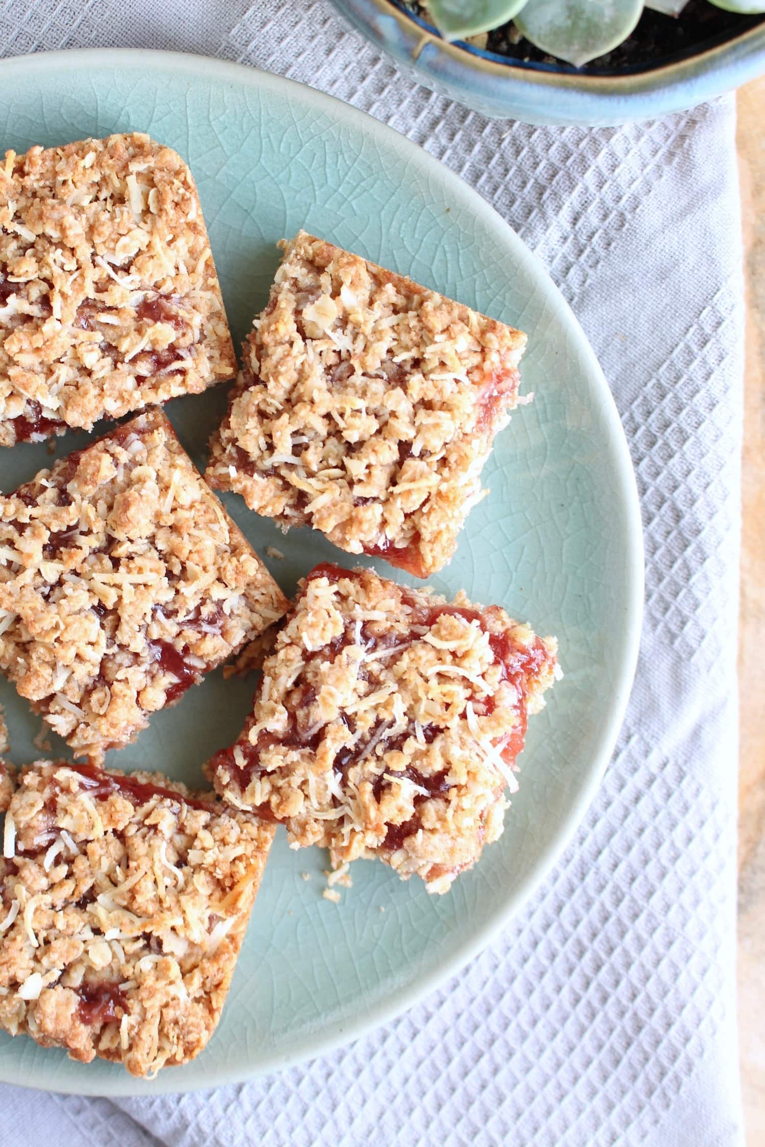 Strawberry jam filled oatmeal bars on a blue plate. 