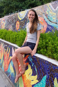 Faith sitting on a mosaic wall in Hanoi, Vietnam