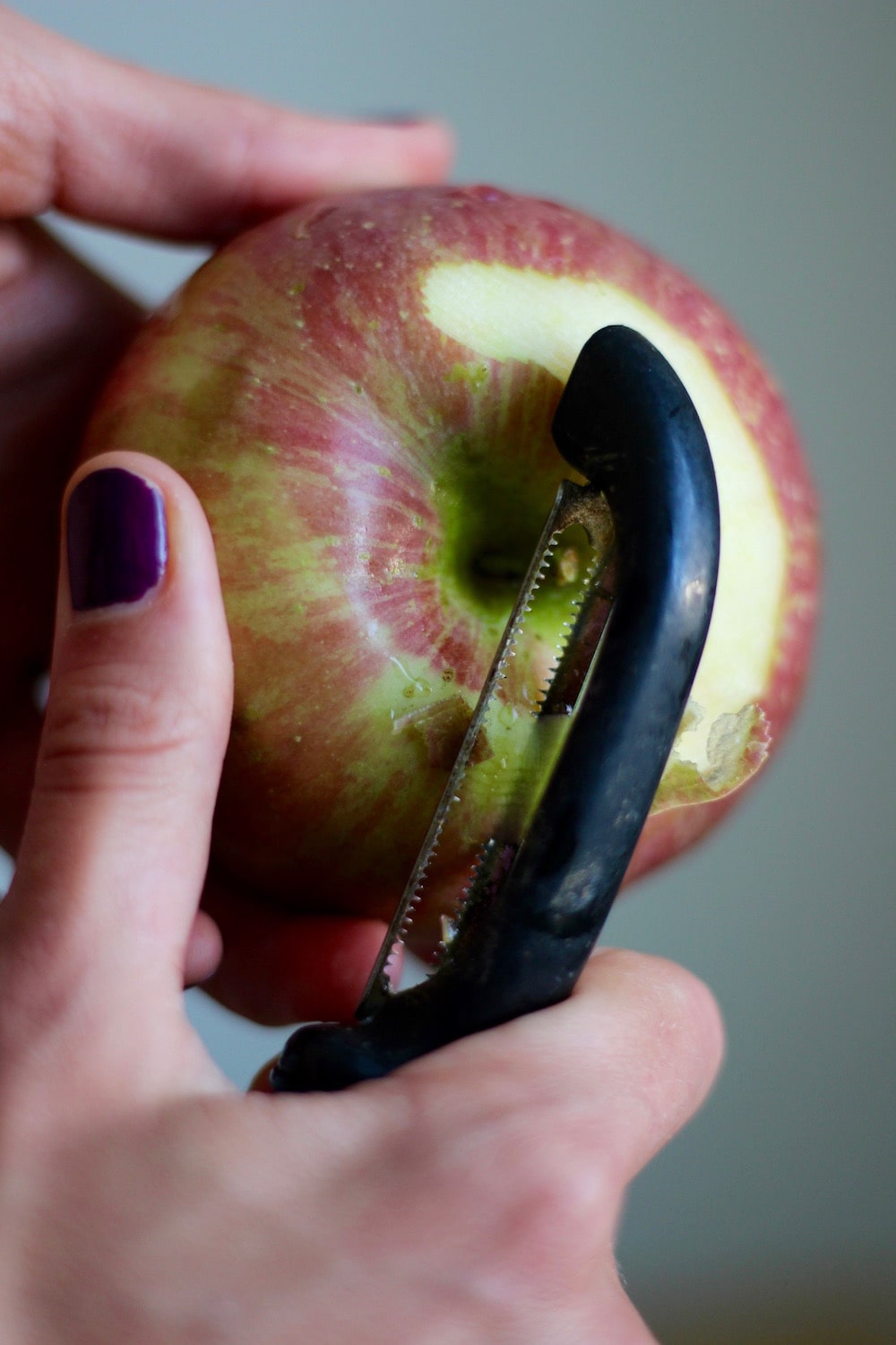 a vegetable peeler peeling the skin off an apples