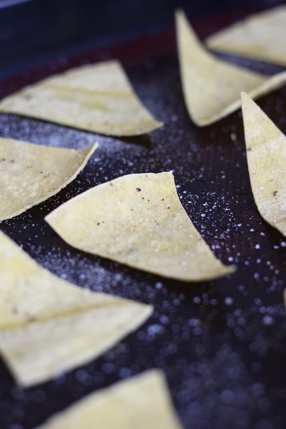 tortilla triangles laid out on a baking sheet sprinkled with salt