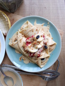 Vegan Crepes topped with jam, bananas, granola and drizzled with peanut butter