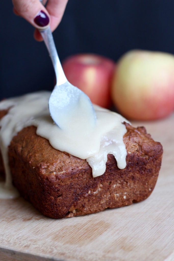 vegan apple cake being glazed with maple glaze