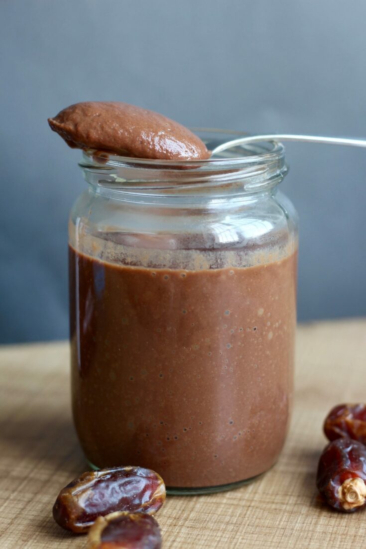 Date Sweetened Chocolate Sauce on a spoon above a jar