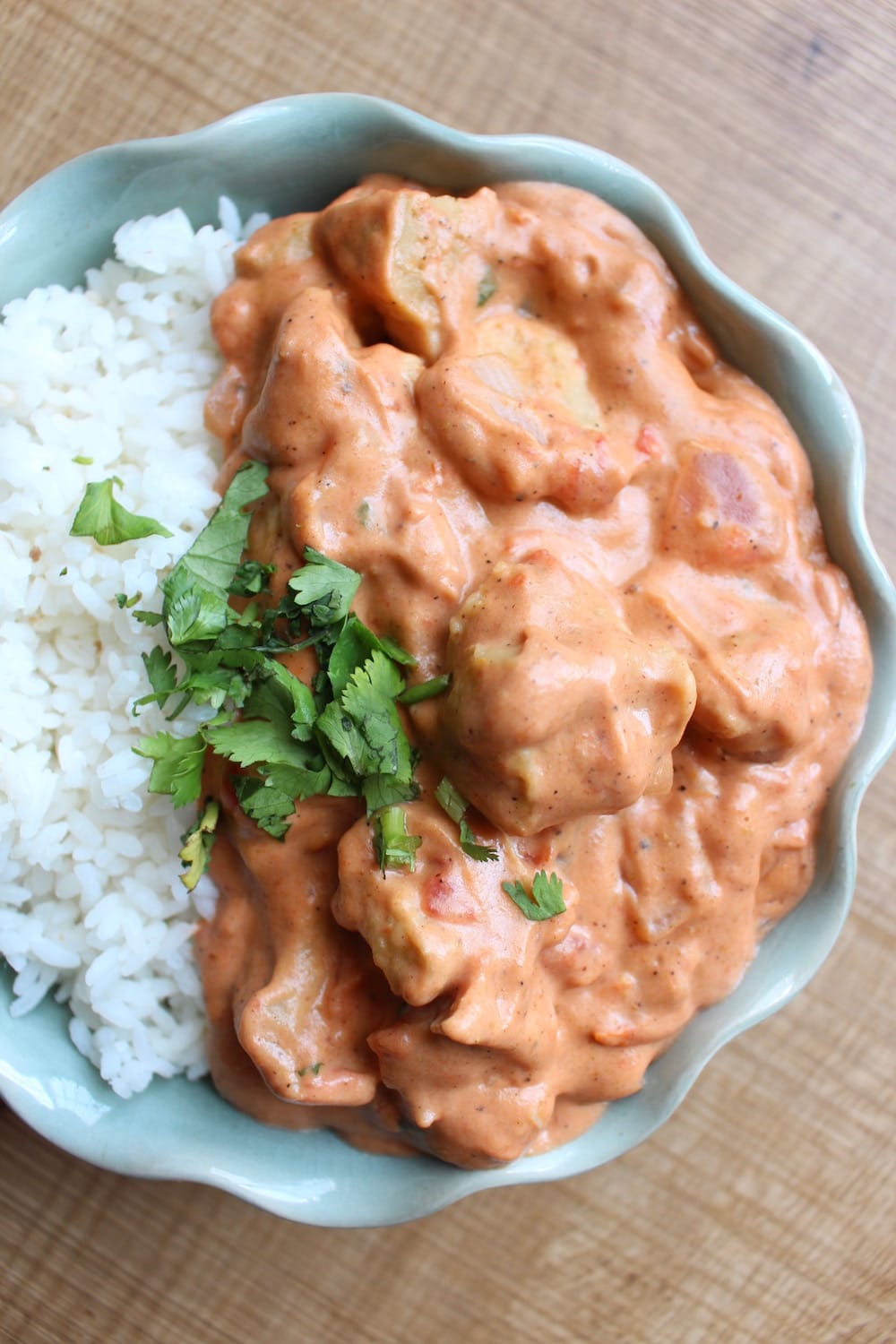 top view of Vegan Seitan Tikka Masala beside rice with green garnish