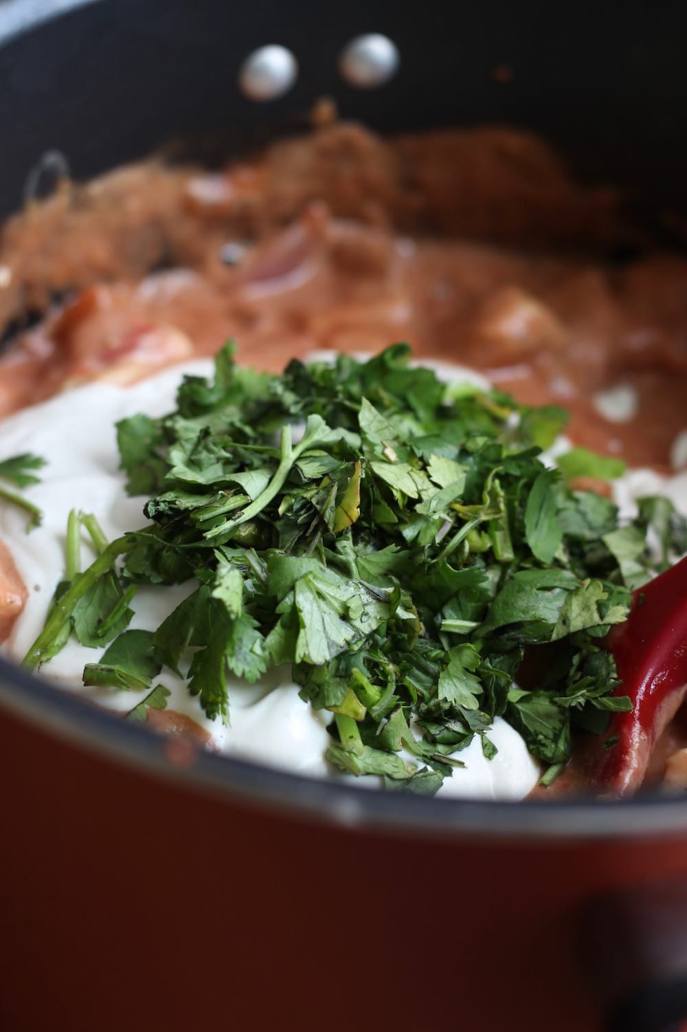 simmering Vegan Seitan Tikka Masala added with greens in a pot