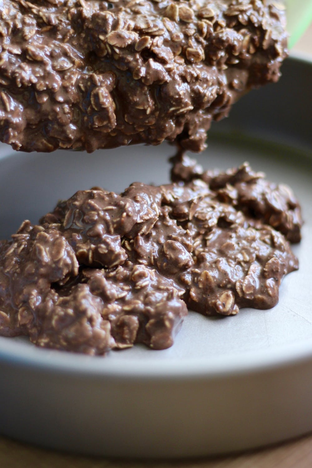 Chocolate oatmeal batter being poured into a round cake pan.