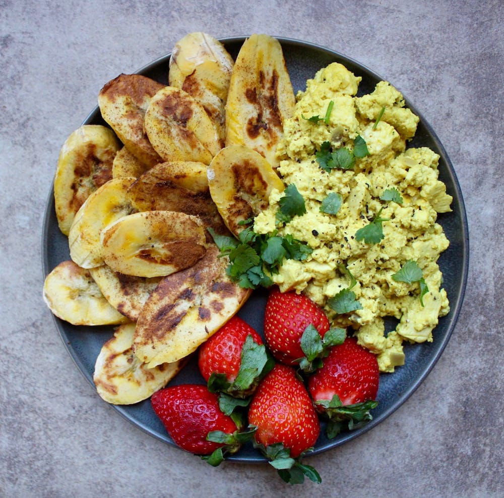 a plateful of scrambled tofu, strawberries and baked raw bananas