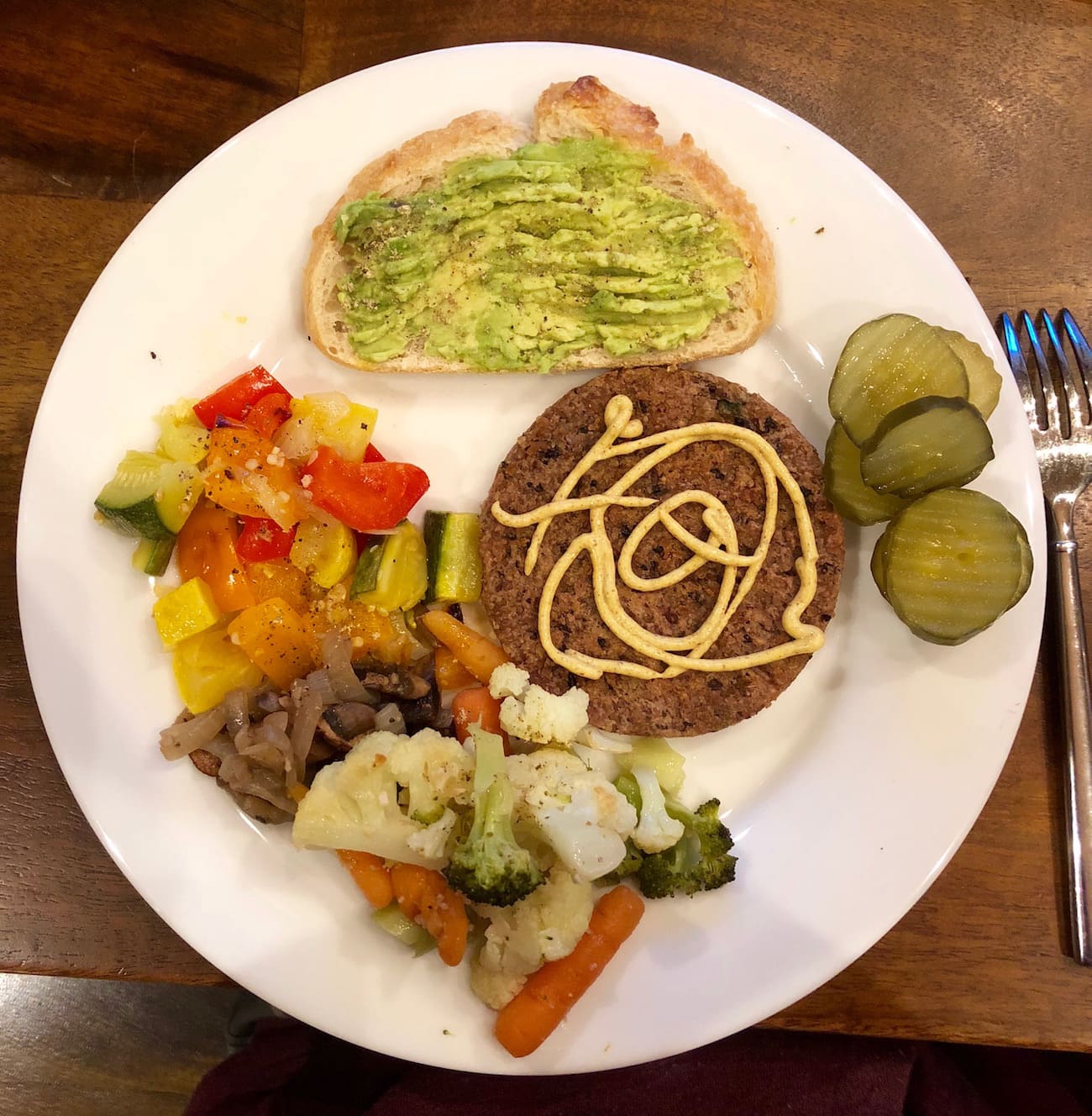 Hilary's Black Bean Burger, avocado toast, roasted veggies and pickles