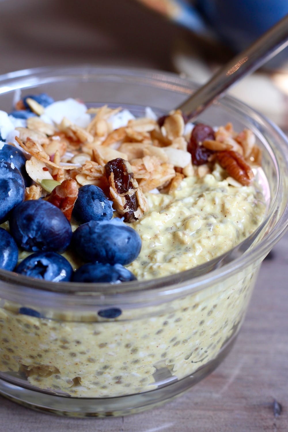 Vegan Golden Milk Overnight Oats in a bowl topped with nuts, raisins and blueberries