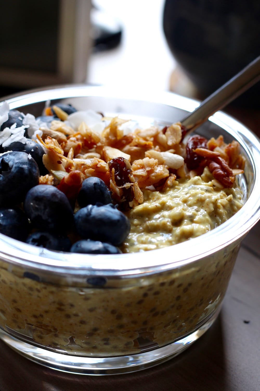 Vegan Golden Milk Overnight Oats in a bowl topped with nuts, raisins and blueberries