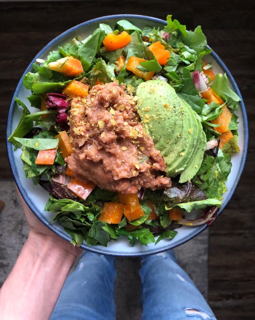 Mixed greens topped with refried beans, avocado and nutritional yeast