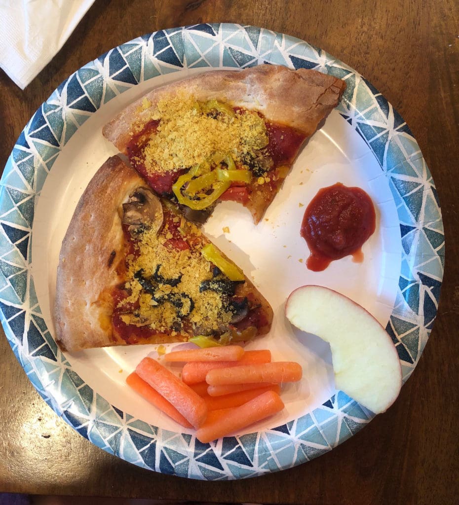 Pizza from Papa John's topped with nutritional yeast with carrots and apples as sides