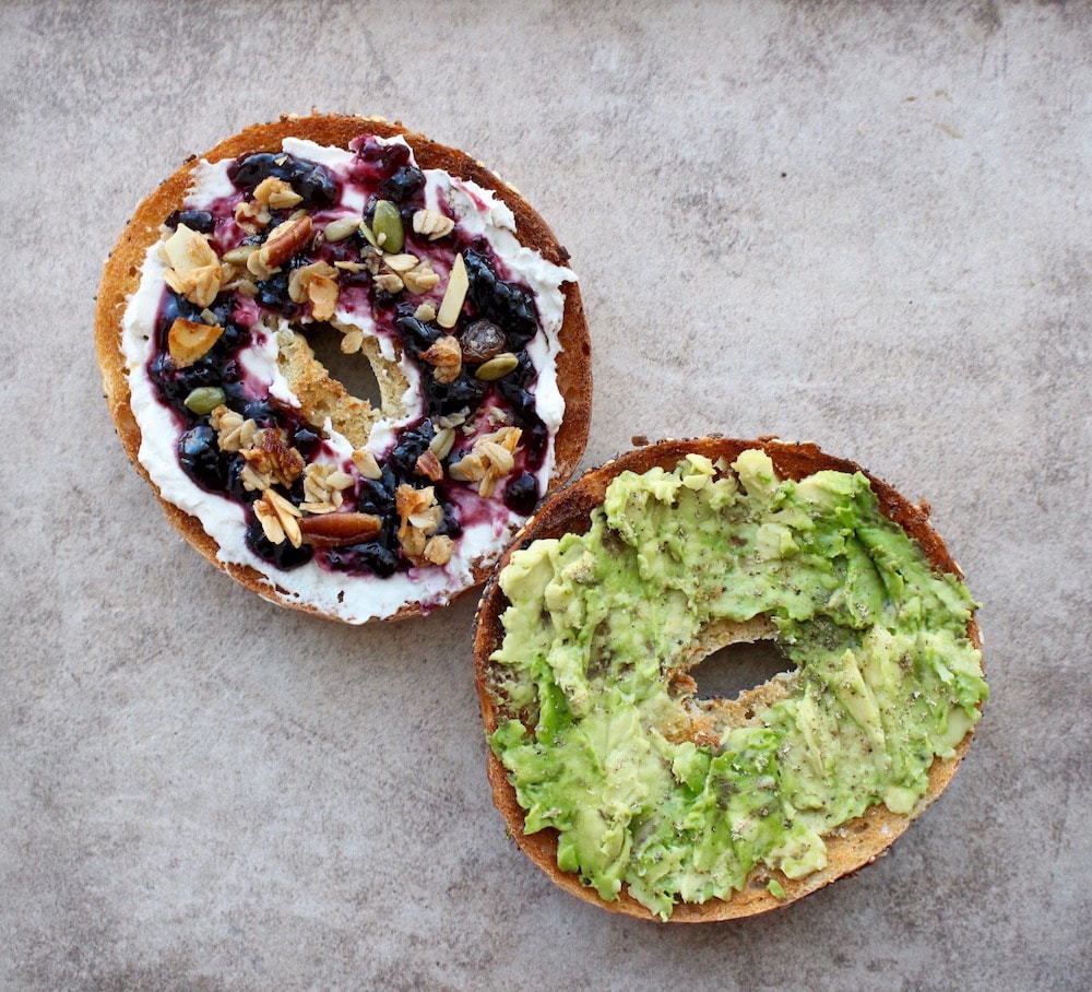 Everything bagel; one side topped with Kite Hill cream cheese, blackberry jam and granola and the other topped with avocado, salt and pepper
