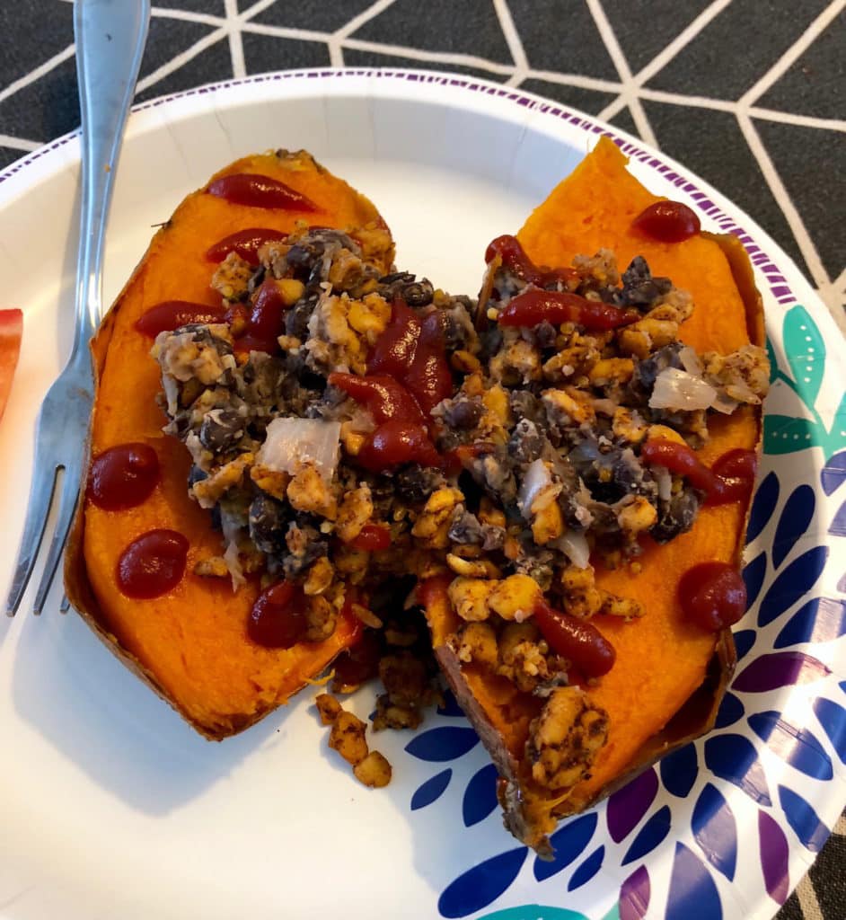 Leftover taco tempeh on top of a baked sweet potato with more beans and ketchup
