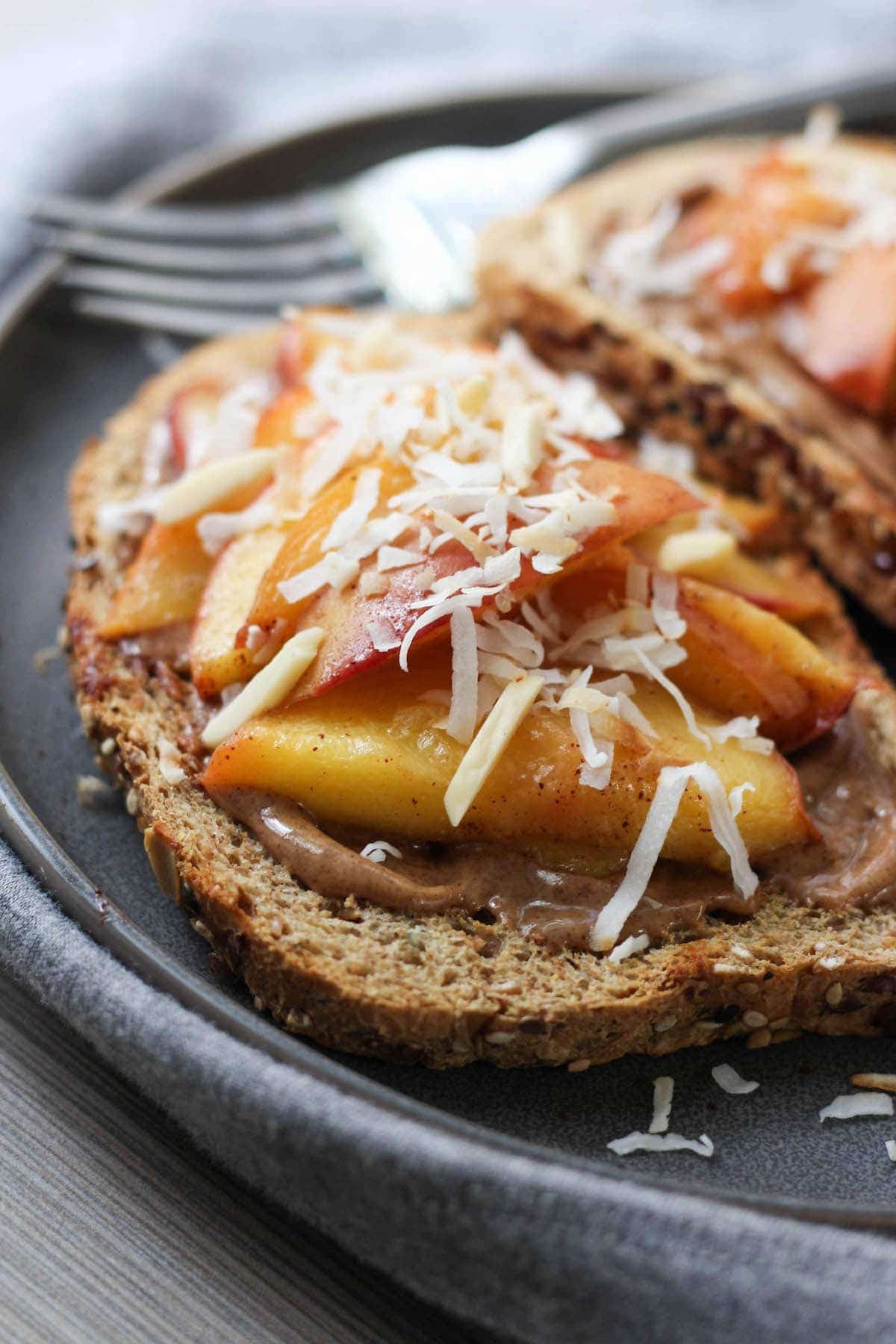 Toasted almonds and coconut on top of cinnamon peach and almond butter toast