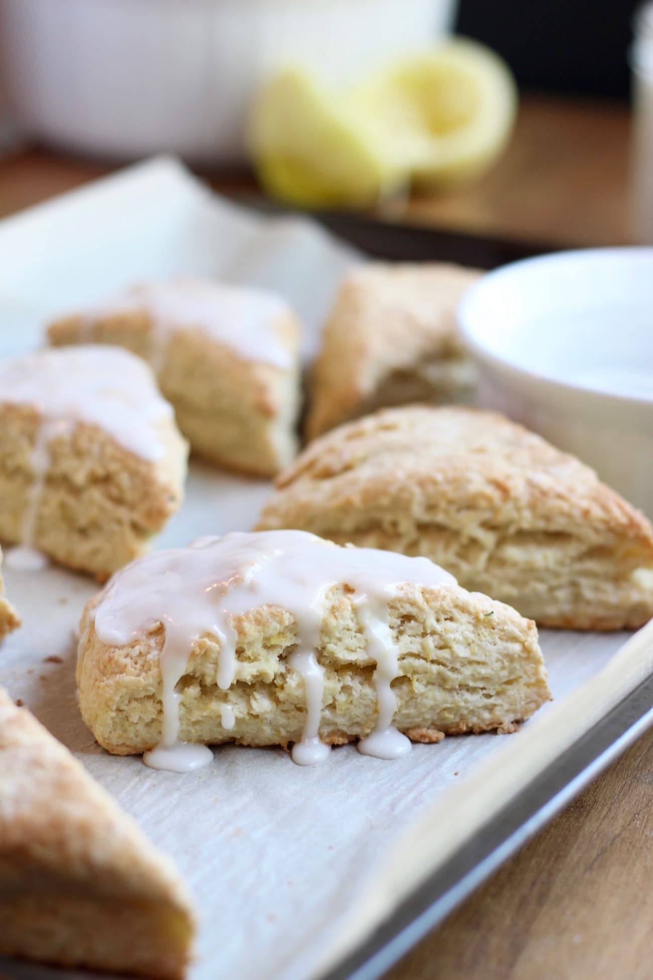 Sugar glaze dripping down the side of a vegan lemon scone