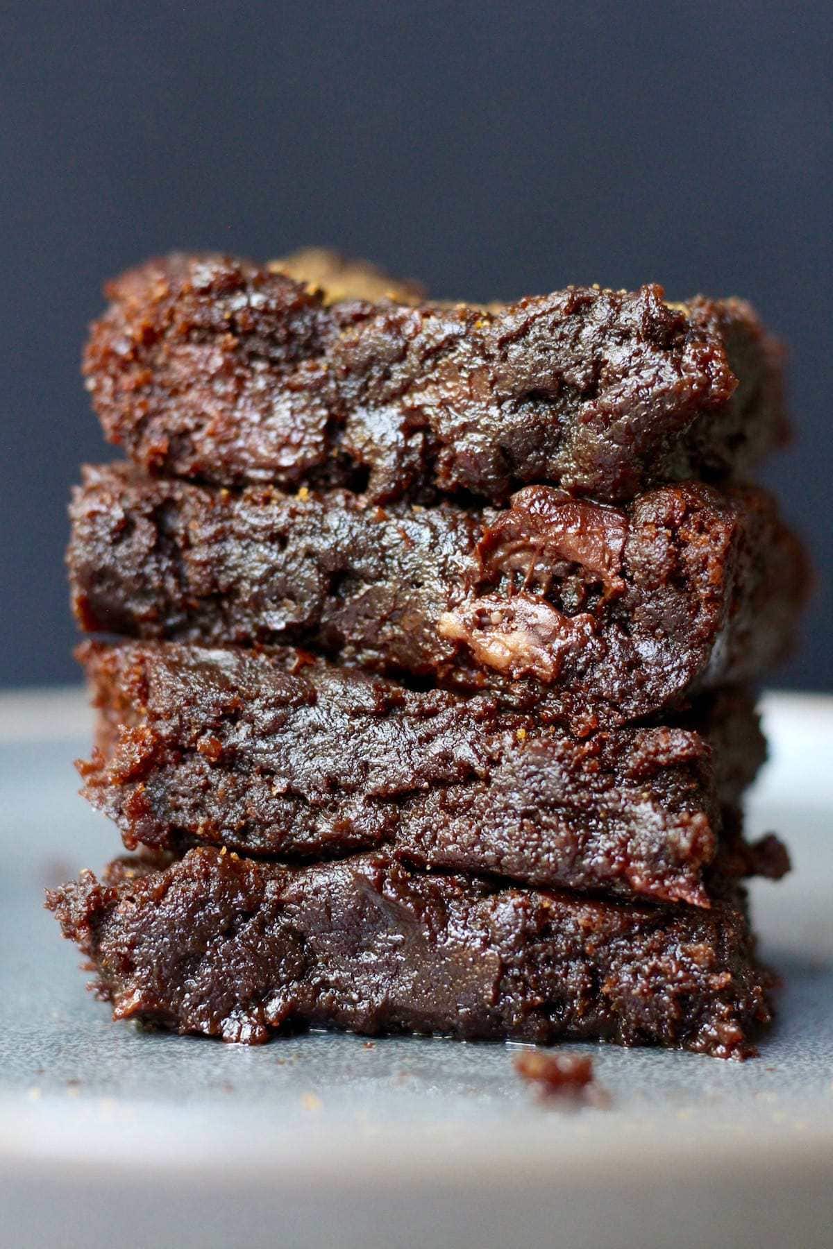 Four gooey vegan tahini brownies stacked on top of each other.
