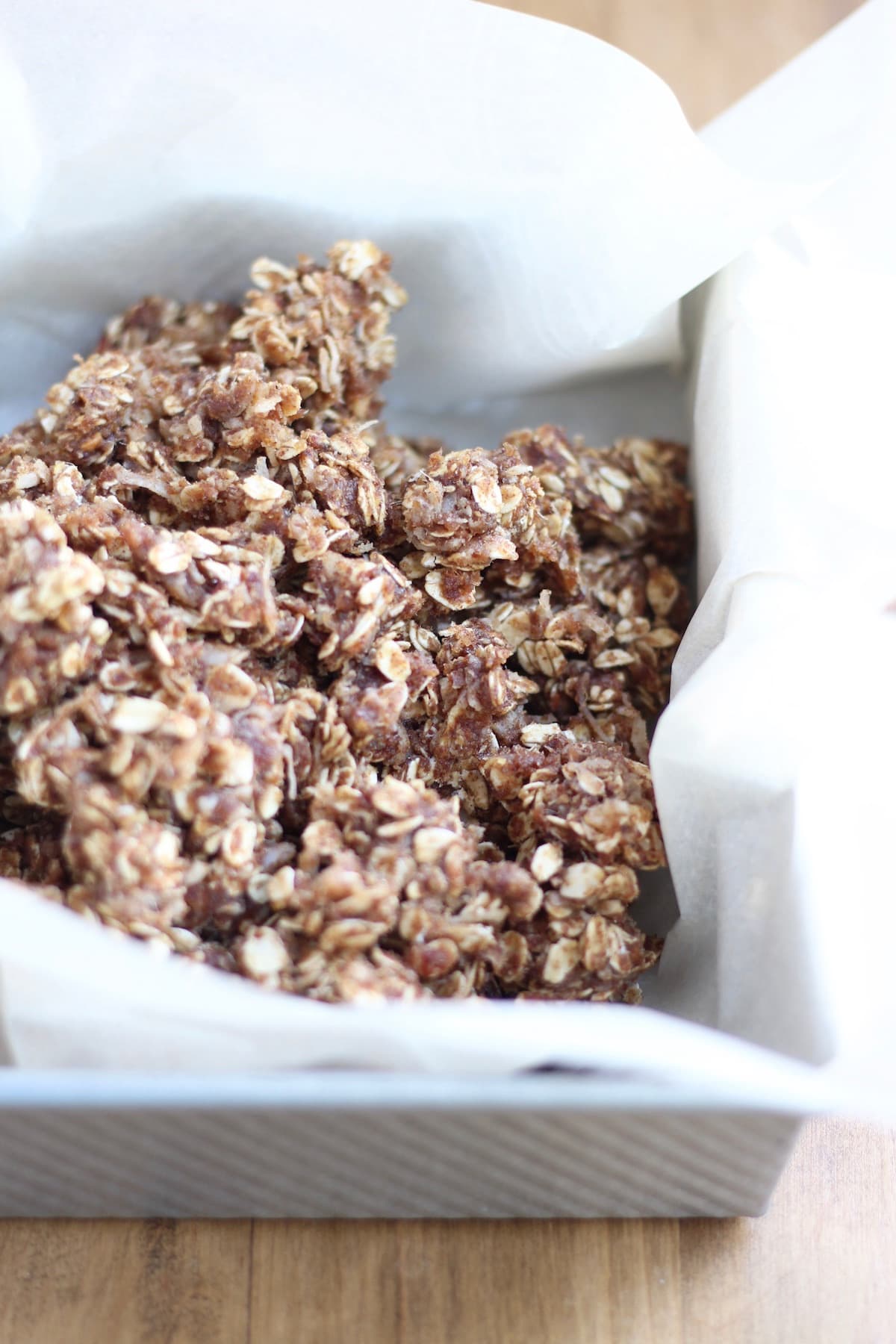 Chewy Almond Butter Date Granola Bars in a parchment paper lined baking dish