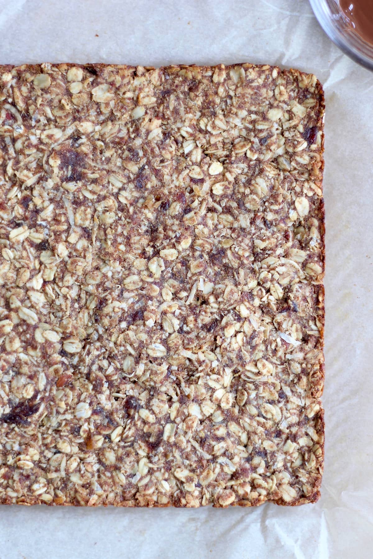 Chewy almond butter date granola bar dough packed into a baking dish