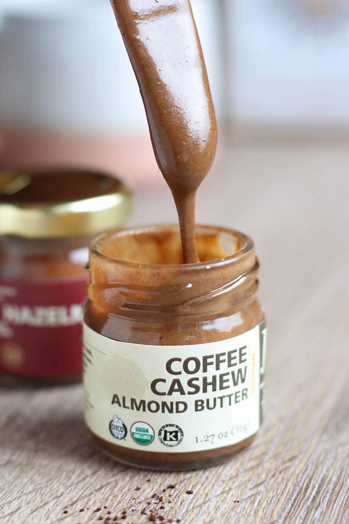 A butter knife drizzling coffee cashew almond butter back into the jar. 