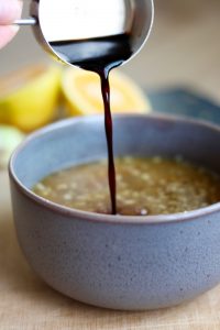 pouring soy sauce into a bowl for orange sauce