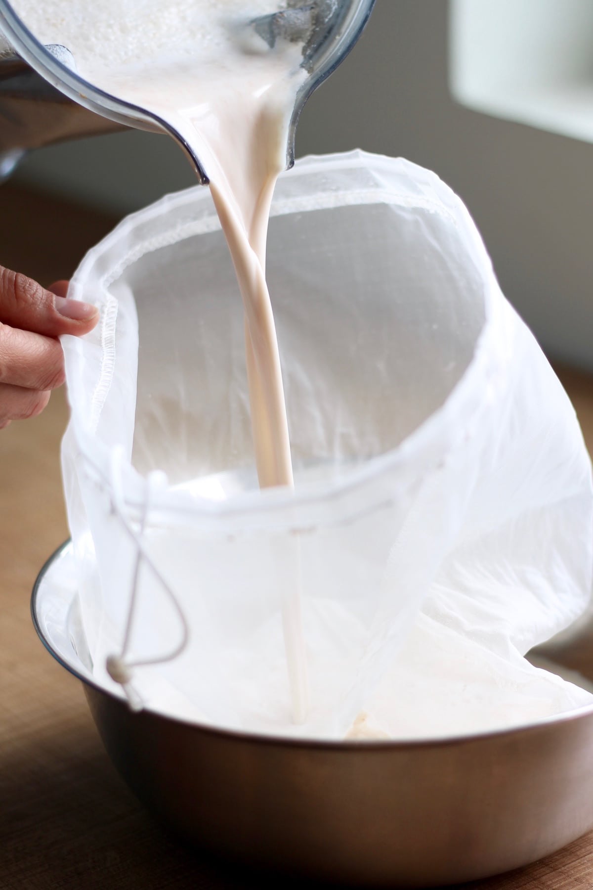Pouring almond milk into a nut milk bag