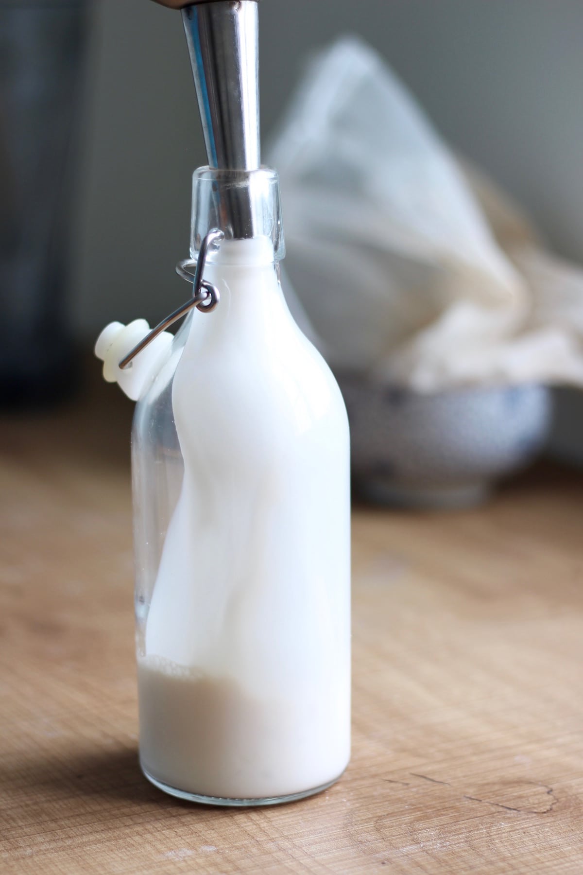 pouring freshly made almond milk into a glass jar