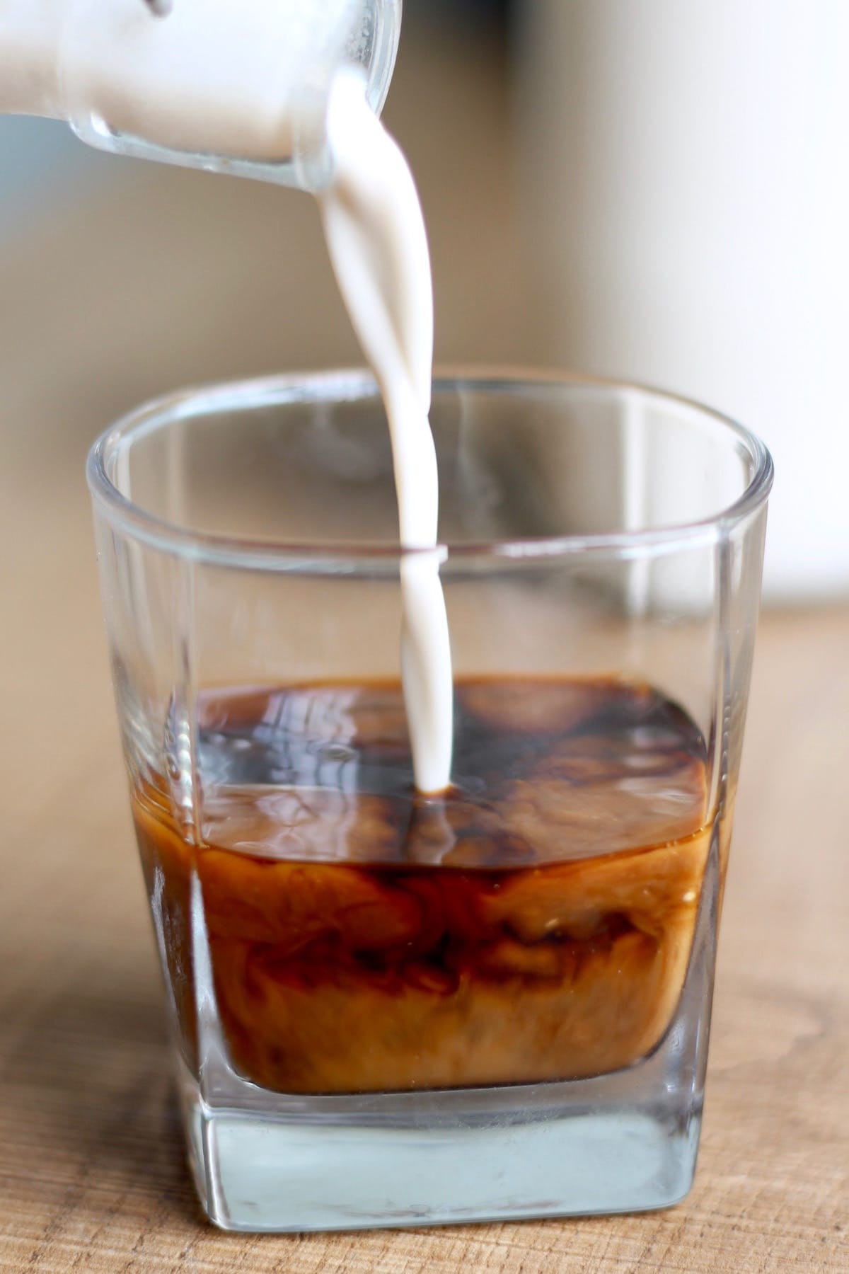 pouring homemade almond milk into cold brew coffee