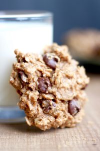 a Peanut Butter chocolate chip cookie resting against a glass of milk