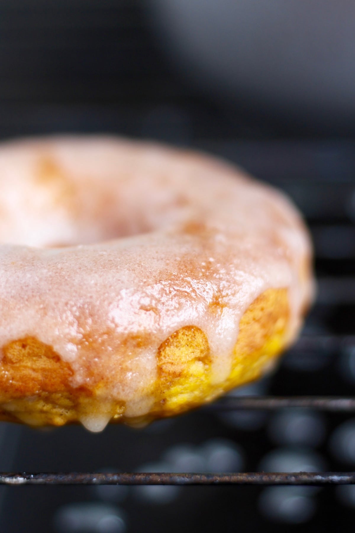 A glazed pumpkin baked donut drying on a wire rack
