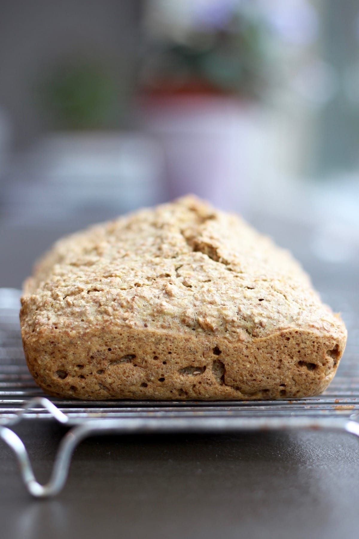 a loaf of brown bread cooling on a wire rack