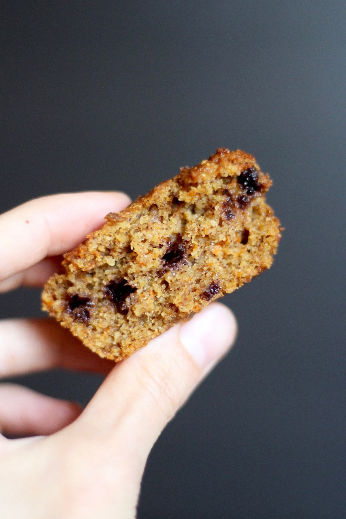 a carrot chocolate chip muffin broken in half revealing melted chocolate chips