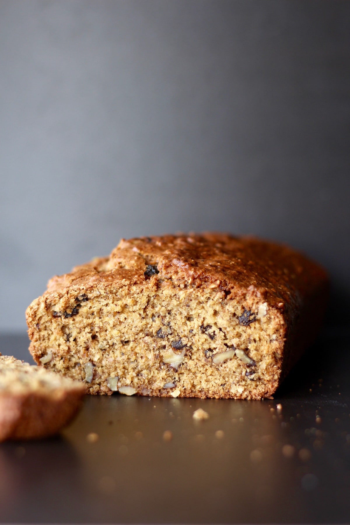 walnuts and raisins peeking out of a sliced loaf of quick bread