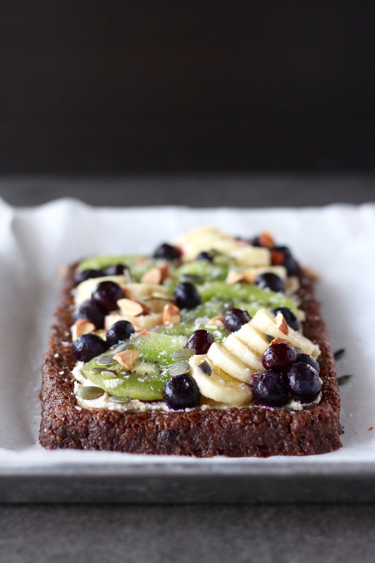 raw fruit pizza displayed on a parchment paper lined baking tray