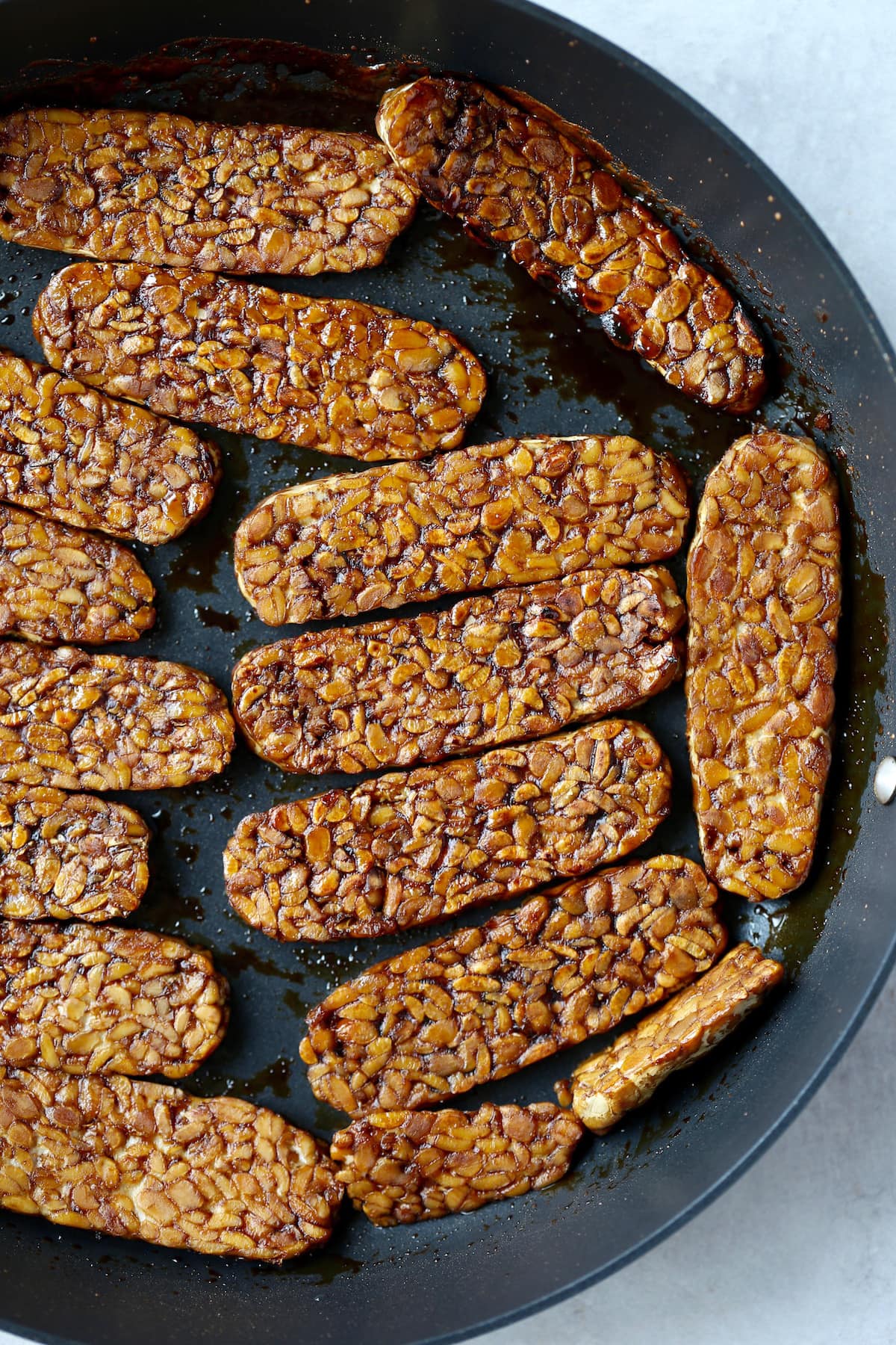 tempeh bacon browning in a pan