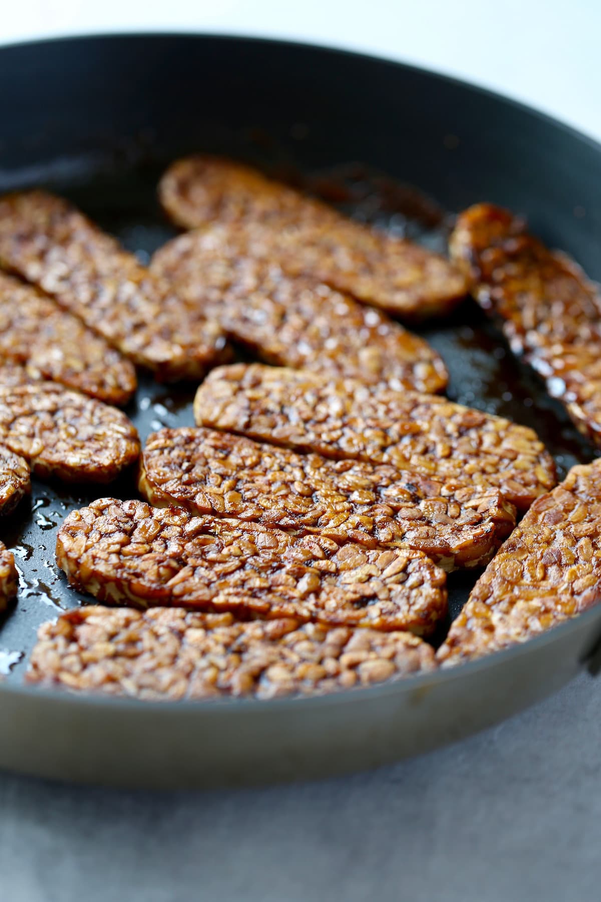 golden brown tempeh cooking in a pan