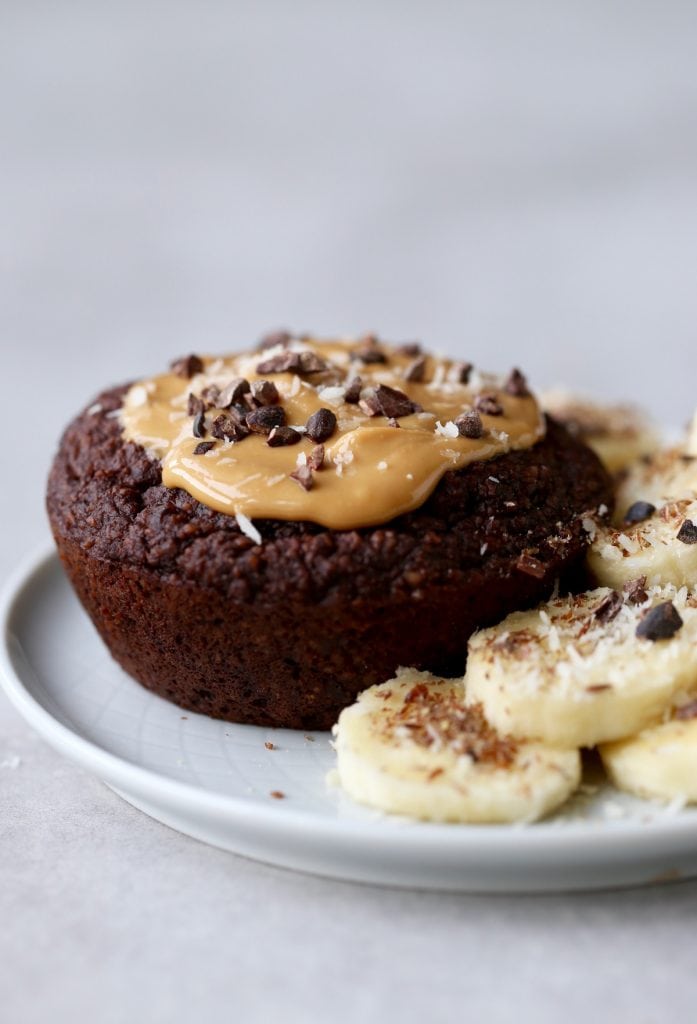 A jumbo chocolate muffin topped with peanut butter and cacao nibs