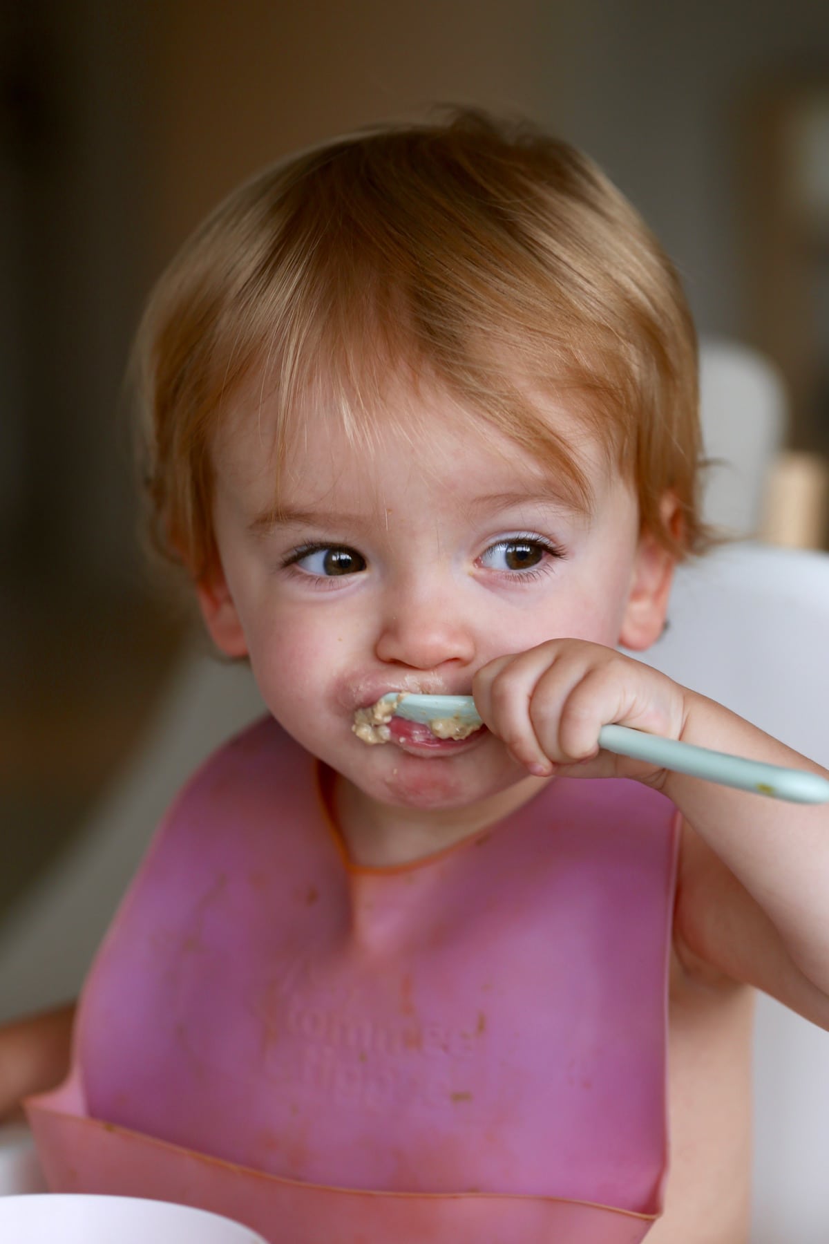 a little girl trying to eat oatmeal with a spoon
