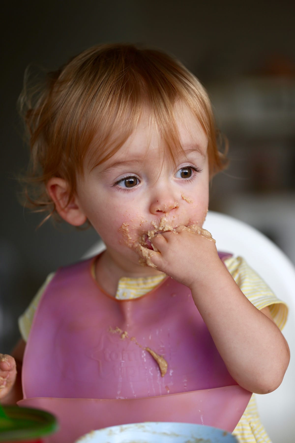 A little girl eating weetbix with her hands