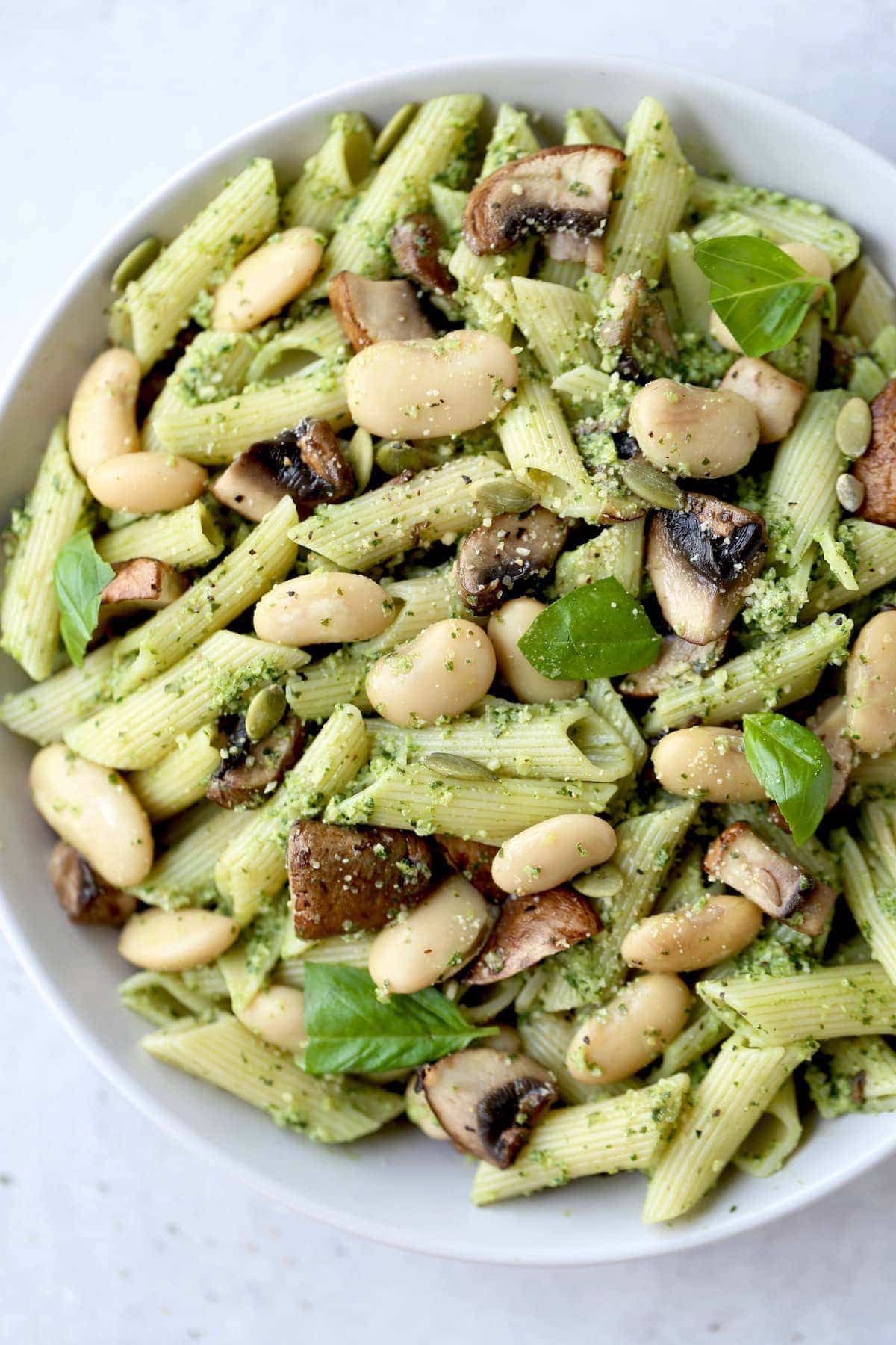 pesto pasta topped with butter beans, basil and mushrooms