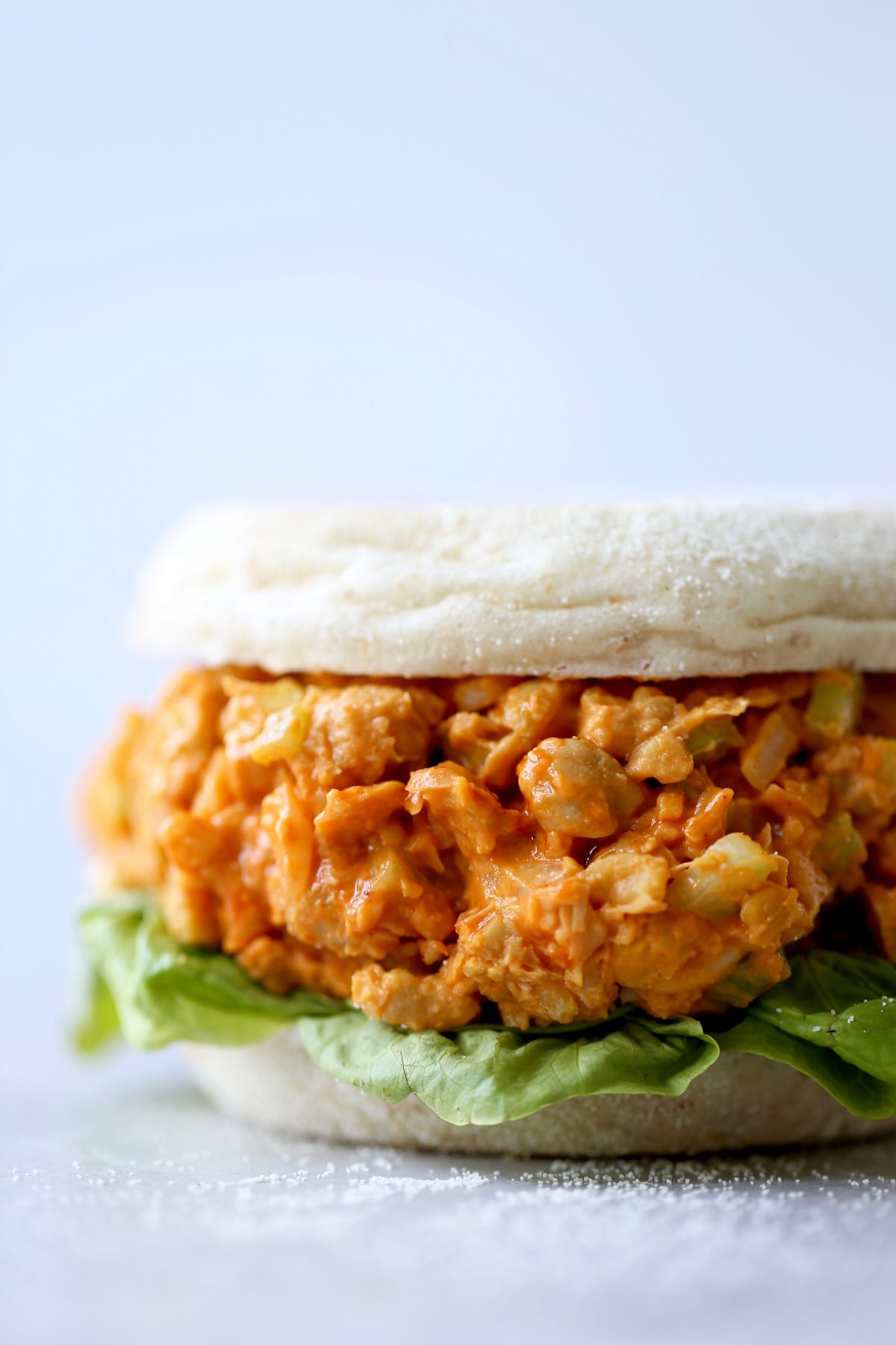 A side shot of a loaded buffalo chickpea salad sandwich with lettuce on it. 