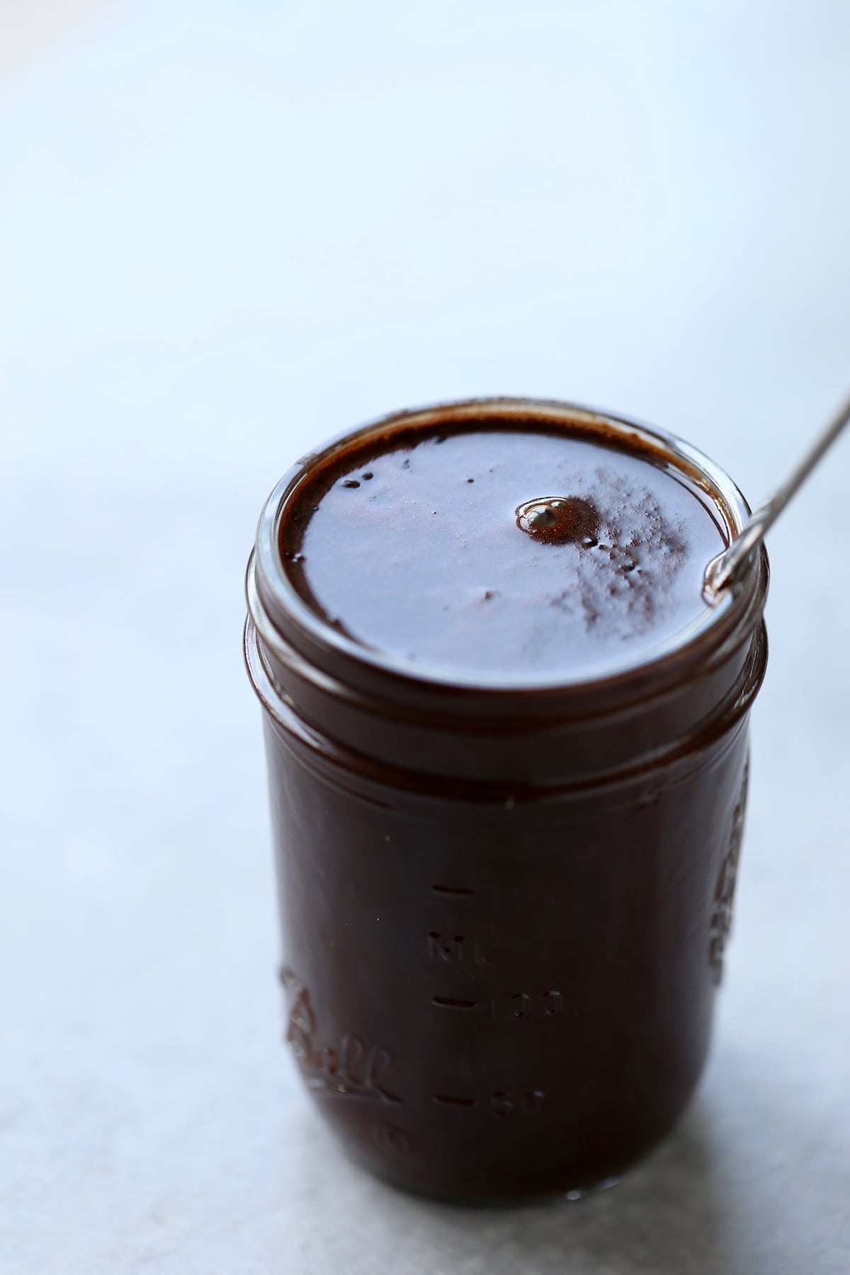 A mason jar full filled to the top with homemade chocolate syrup.