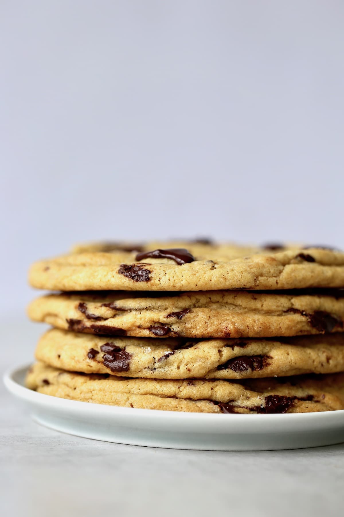 four jumbo chocolate chip cookies stacked on a plate