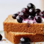 2 slices of Whole Wheat Olive Oil Tea Cake topped with blueberries on a plate